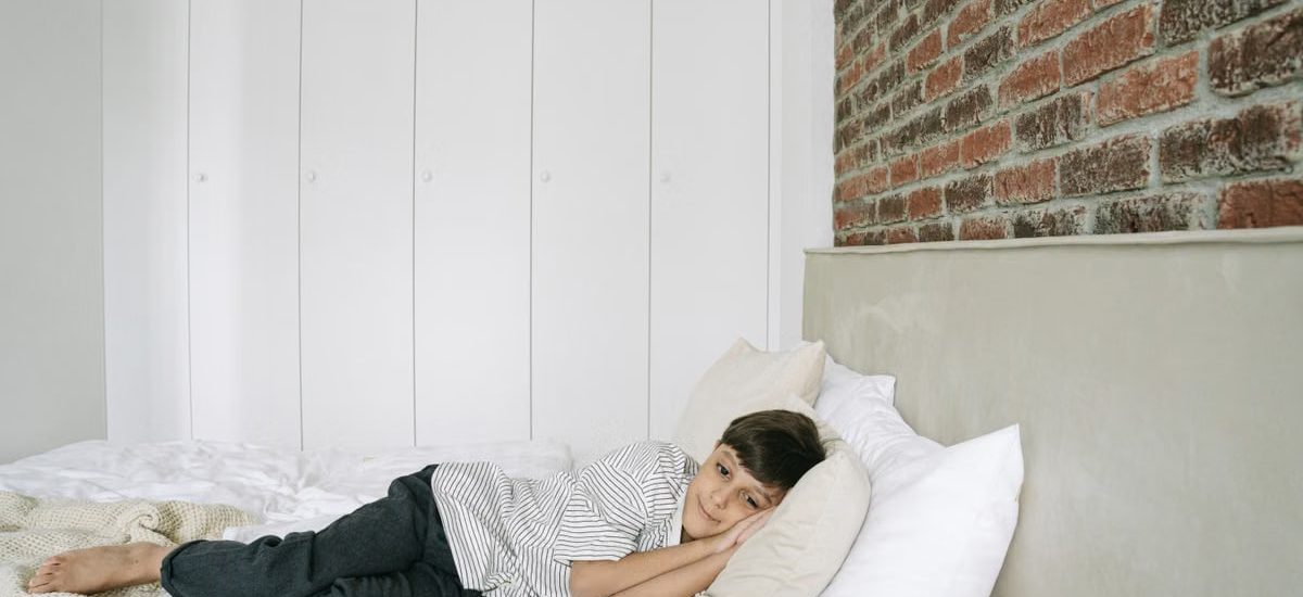 A young boy lying comfortably on a bed in a stylish and minimalist bedroom.