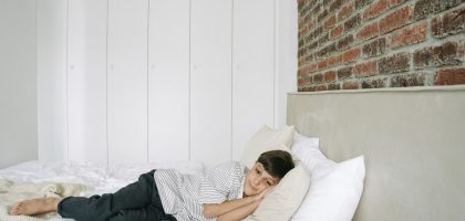 A young boy lying comfortably on a bed in a stylish and minimalist bedroom.