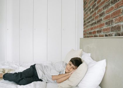 A young boy lying comfortably on a bed in a stylish and minimalist bedroom.